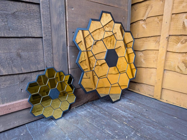 May include: Two black framed mirrors with gold hexagonal tiles. The larger mirror is about 18 inches in diameter and the smaller mirror is about 10 inches in diameter.