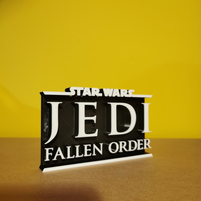 May include: A black and white 3D printed sign with the text "STAR WARS JEDI FALLEN ORDER".