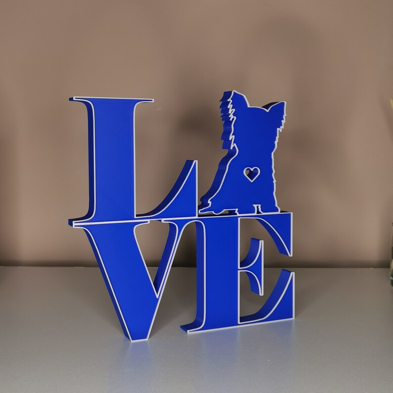 May include: Blue wooden cutout of the word "LOVE" with a silhouette of a Yorkshire Terrier dog in the center of the "O".