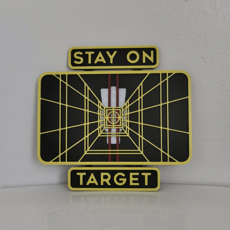 May include: A yellow and black target sign with the words "Stay On Target" above and "Target" below. The target is a black and white grid with a red and white stripe in the center.