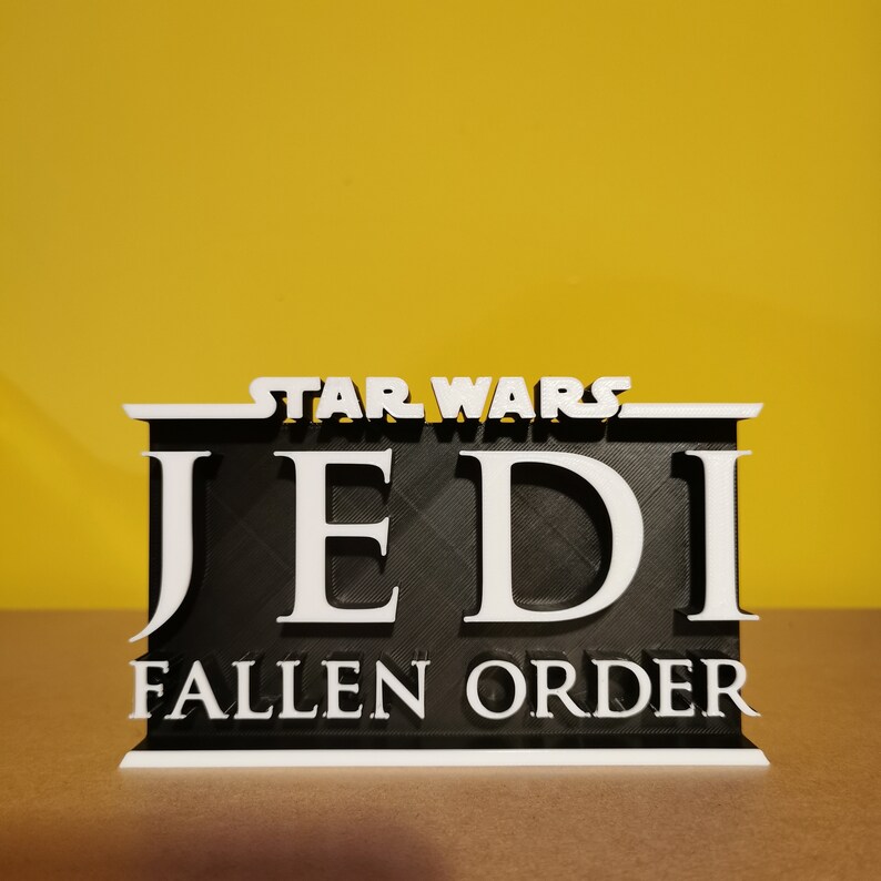 May include: A black and white 3D printed sign with the text "Star Wars Jedi Fallen Order".