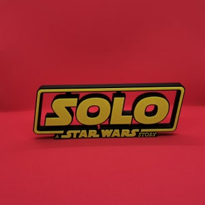 May include: A black and yellow sign with the word "SOLO" in large yellow letters. The sign also says "A STAR WARS STORY" in smaller letters.
