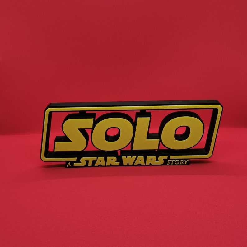 May include: A black and yellow sign with the word "SOLO" in large yellow letters. The sign also says "A STAR WARS STORY" in smaller letters.