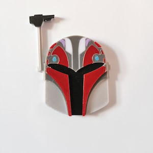 May include: A 3D printed Mandalorian helmet with a red and gray color scheme. The helmet has a black visor and blue accents.