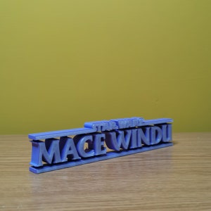 May include: A purple 3D printed sign that reads "STAR WARS MACE WINDU".