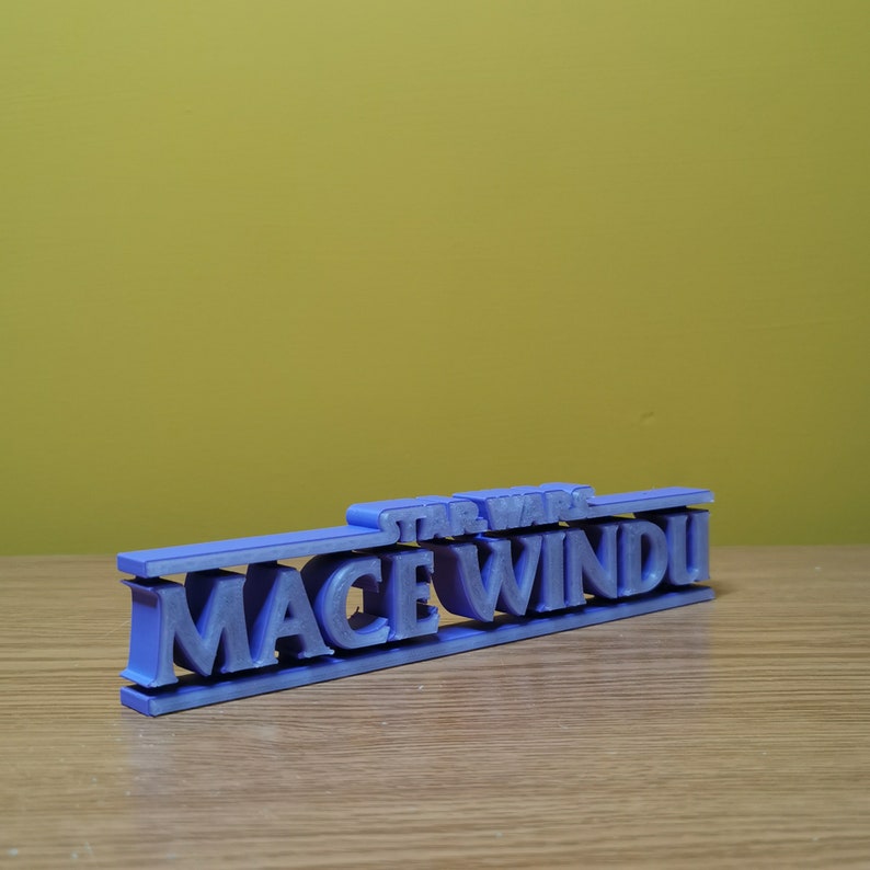May include: A purple 3D printed sign that reads "STAR WARS MACE WINDU".