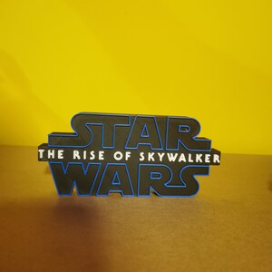 May include: A black 3D printed Star Wars logo with blue outlines. The text "The Rise of Skywalker" is printed below the logo.