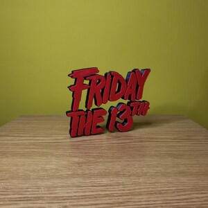 May include: A red and black 3D printed sign that reads "Friday the 13th".