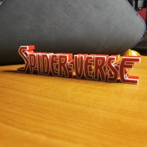 May include: A red 3D printed sign that reads "SPIDER-VERSE".