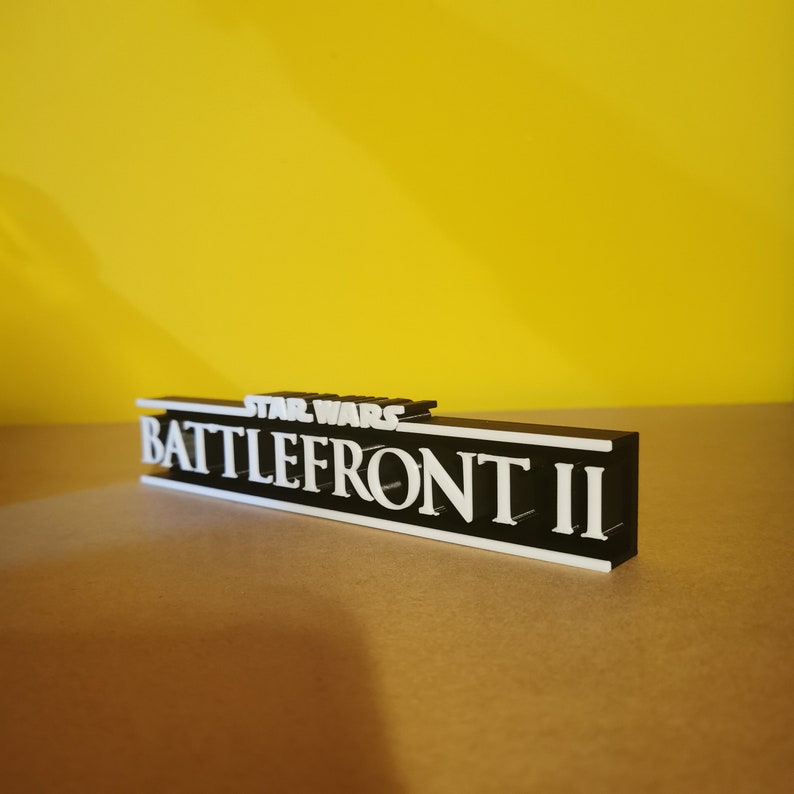 May include: A black and white 3D printed sign with the text "STAR WARS BATTLEFRONT II" in white letters on a black background.