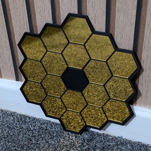 May include: A gold mirror with a honeycomb design. The mirror is made up of many small hexagonal mirrors that are arranged in a circular pattern. The mirror is surrounded by a black frame.