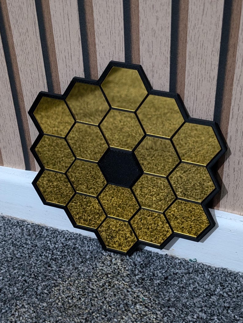 May include: A gold mirror with a honeycomb design. The mirror is made up of many small hexagonal mirrors that are arranged in a circular pattern. The mirror is surrounded by a black frame.