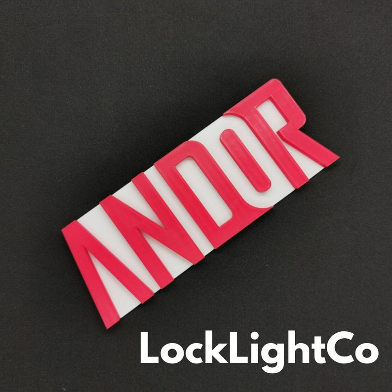 Op de afbeelding: Een rechthoekig, rood en wit bord met het woord "ANDOR" in vette, rode letters. Het bord is schuin, waarbij de letters verhoogd lijken. De tekst "LockLightCo" is in het wit onderaan gedrukt.