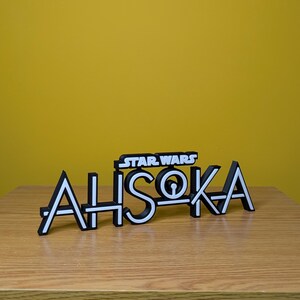 May include: A black and white 3D printed sign that reads "STAR WARS AHSOKA".