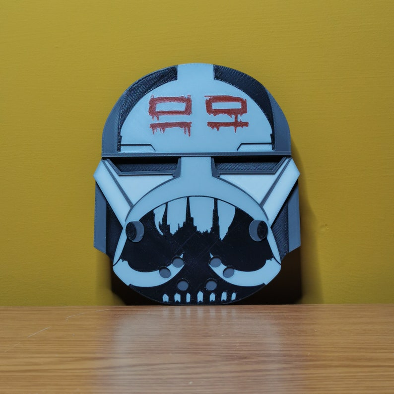 Pu&ograve; includere: Un casco stampato in 3D bianco e nero con un "99" rosso dipinto sul davanti. Il casco ha un design bianco e nero sul fondo.