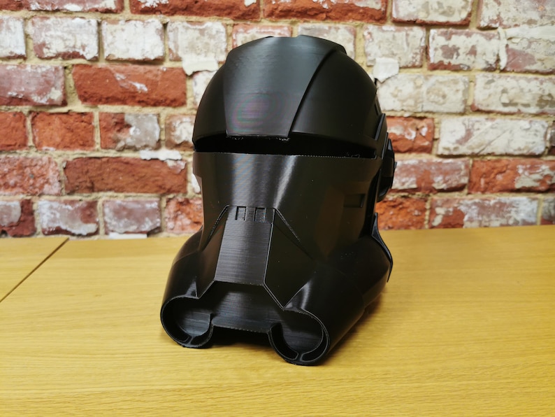 Puede incluir: Un casco de pl&aacute;stico negro con un dise&ntilde;o detallado, que se asemeja al casco de un soldado futurista.