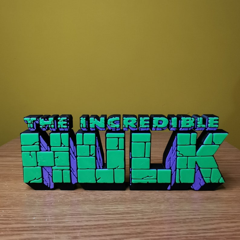 K&ouml;nnte beinhalten: Ein gr&uuml;nes und violettes 3D-Buchstaben-Schild mit der Aufschrift "THE INCREDIBLE HULK".