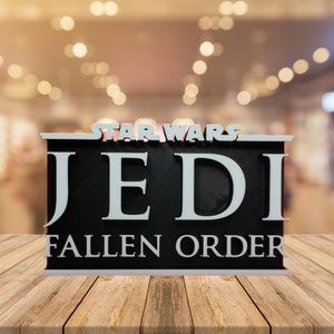 Könnte beinhalten: Ein schwarz-weißes 3D-gedrucktes Schild mit dem Text "STAR WARS JEDI FALLEN ORDER" in weißen Buchstaben auf schwarzem Hintergrund.