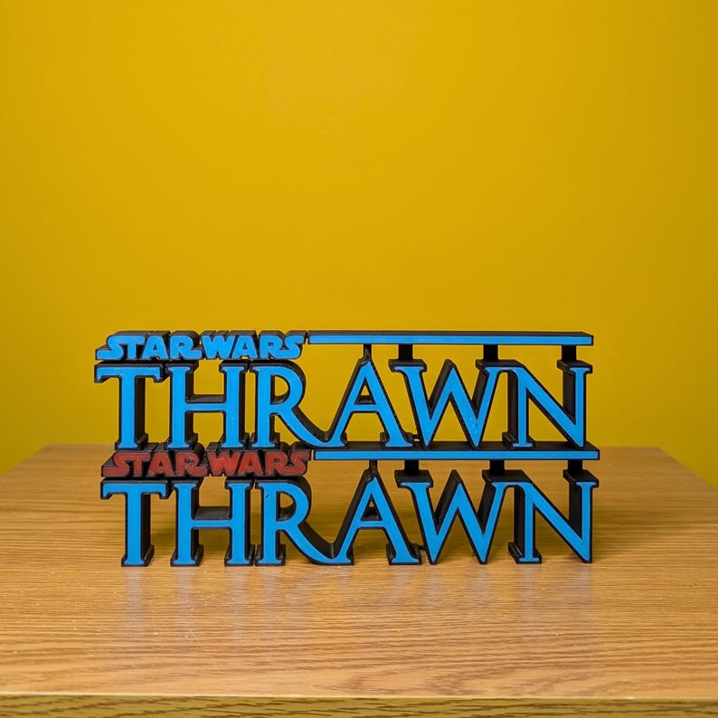 May include: A 3D printed model of the Star Wars character Thrawn's name in blue with the words "Star Wars" in red above and below the name.