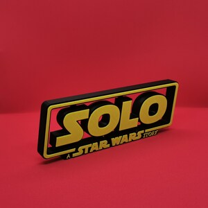 May include: A black and yellow 3D sign with the text "SOLO: A STAR WARS STORY".