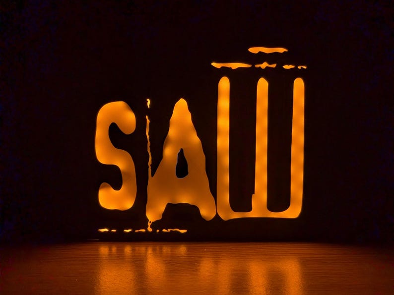 May include: A black and orange light-up sign with the word "SAW" and a silhouette of a trash can.