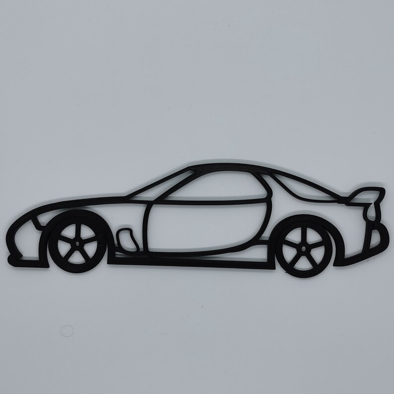 May include: Black line art silhouette of a sports car. The car is facing to the right and has a rounded body style.