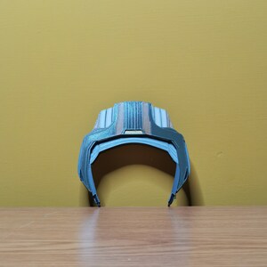 Pu&ograve; includere: Un cerchietto di plastica blu e marrone con un design geometrico. Il cerchietto &egrave; curvo e ha una superficie liscia.