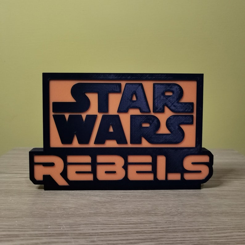 May include: A black and orange 3D printed sign with the text "Star Wars Rebels".