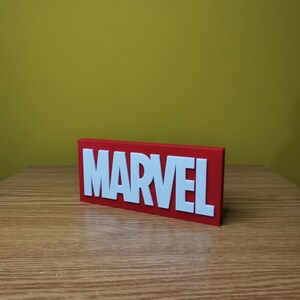 May include: A red rectangular sign with the word "MARVEL" in white raised letters.