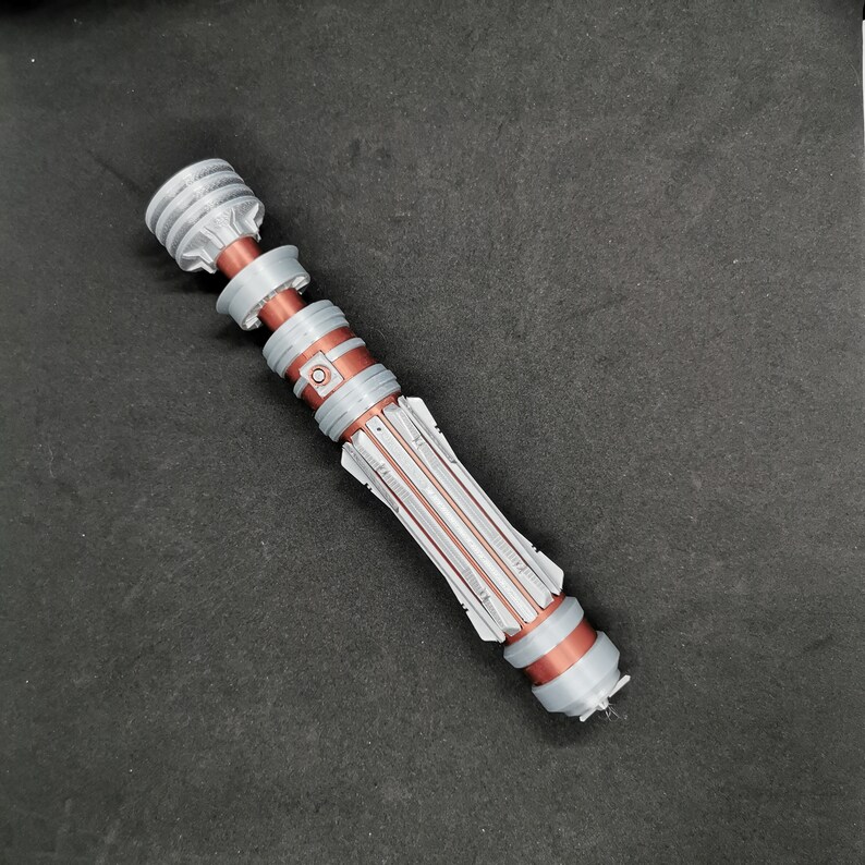 May include: A silver and copper lightsaber prop with a textured handle and a black tip.