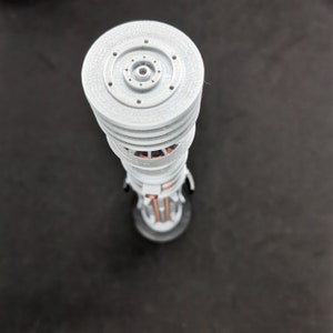 May include: A white 3D printed model of a tower with a circular top and multiple layers. The tower has a copper-colored interior.