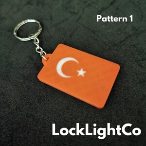 May include: Orange keychain with a white crescent moon and star design. The keychain is labeled "Pattern 1" and "LockLightCo".