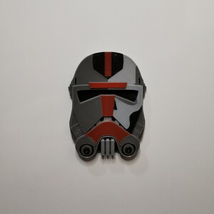 May include: A 3D printed helmet in gray, black, white, and red. The helmet has a visor and a design that resembles a Star Wars character.