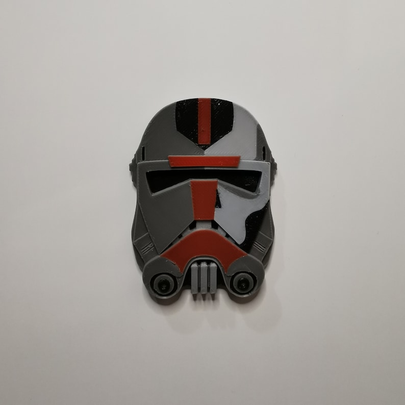 May include: A 3D printed helmet in gray, black, white, and red. The helmet has a visor and a design that resembles a Star Wars character.