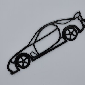 May include: Black line art silhouette of a sports car with a spoiler. The car is facing to the right and the wheels are visible.