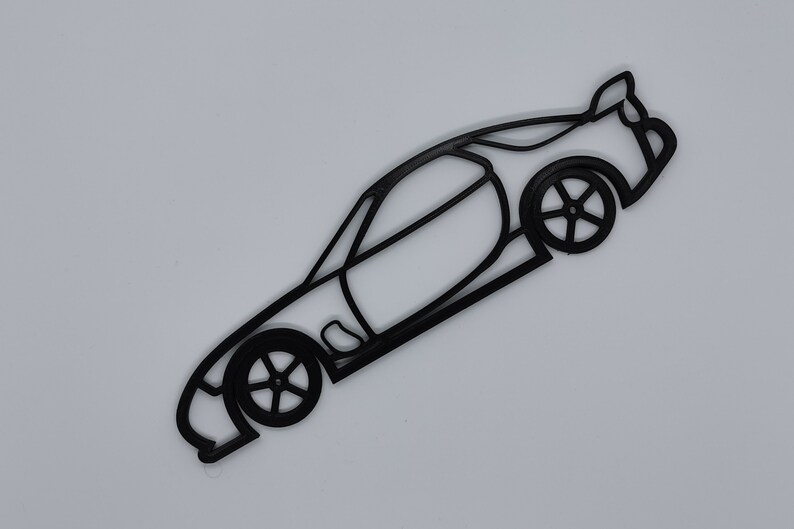 May include: Black line art silhouette of a sports car with a spoiler. The car is facing to the right and the wheels are visible.