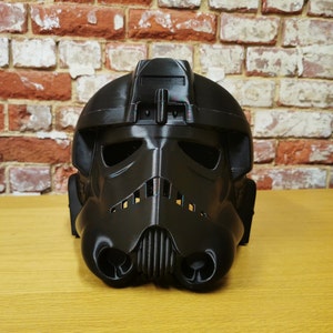 May include: A black plastic helmet with a detailed design, resembling a futuristic soldier's helmet.