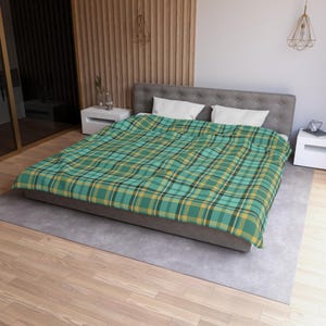May include: A bed with a green, yellow, and black plaid blanket. The blanket covers the bed and has a classic plaid pattern. The bed is gray and has two white pillows. The room has wooden paneling and a light gray rug.