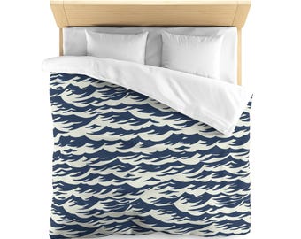 May include: A navy blue and white duvet cover with a wave pattern. The duvet cover is on a bed with white pillowcases.