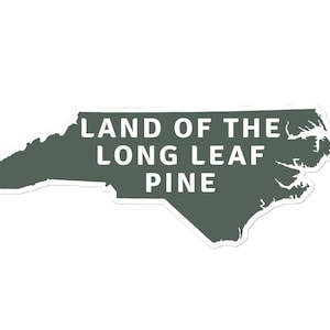 Puede incluir: Un contorno verde del estado de Carolina del Norte con el texto "LAND OF THE LONG LEAF PINE" en blanco.