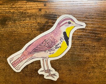 以下が含まれることがあります： 長いとがったくちばしを持つ黄色、黒、紫の鳥のステッカー。鳥は羽を閉じて枝に立っています。