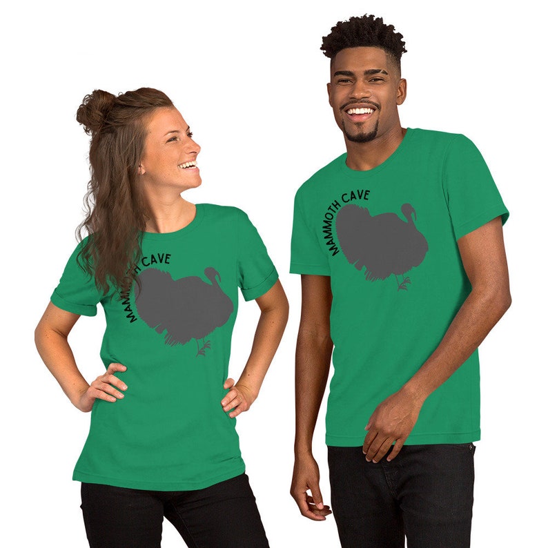 May include: Two people wearing green t-shirts with a silhouette of a turkey and the text "Mammoth Cave" printed on the front.