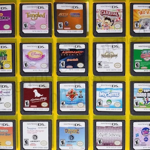 May include: A collection of 18 Nintendo DS game cartridges in a yellow plastic case. The cartridges are arranged in a grid of 4 rows and 5 columns. The cartridges are all different colors and have different game titles on them. Some of the titles include "Tangled", "Plants vs. Zombies", "My Sims", and "Super Mario Bros."