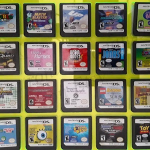 May include: A collection of 18 Nintendo DS game cartridges displayed on a yellow background. The cartridges are arranged in a grid of three rows and six columns. The cartridges are all different colors and feature various characters and logos. Some of the games include Super Mario, Math Blaster, Up, Jonas, iCarly 2, Hannah Montana, and Brain Boost.