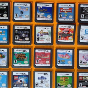 Puede incluir: Una colección de 16 cartuchos de juego de Nintendo DS que se muestran en una caja de plástico amarilla. Los cartuchos están dispuestos en cuatro filas de cuatro. Los cartuchos son de diferentes colores y tienen diferentes títulos, que incluyen "Call of Duty 4", "Hamster Life 2", "Tinker Bell", "MySims Kingdom", "Escape Museum", "Club Penguin", "Orcs & Elves", "Hannah Montana", "Barnyard", "USA Today", "Super Mario", "Animal Crossing", "Hannah Montana", "Hello Kitty", "My Scene", "Lego Harry Potter", "The Smurfs", "Shape Afrika", "Lego Star Wars".