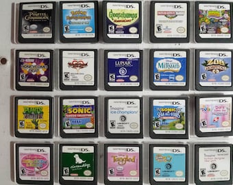 Op de afbeelding: Een verzameling van 18 Nintendo DS-spelcartridges, tentoongesteld in een doorzichtige plastic doos. De cartridges zijn gerangschikt in drie rijen van zes, waarbij elke cartridge een andere speltitel en coverart heeft. Sommige van de spellen zijn Plants vs Zombies, Sonic Classic Collection en Dora the Explorer.