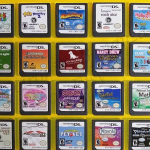 May include: A collection of 18 Nintendo DS game cartridges displayed in a yellow plastic case. The cartridges are arranged in three rows of six. The cartridges feature a variety of games, including "Rubik's World", "Petz Nursery 2", "Madagascar 3", "Imagine: Rock Star", "Hello Kitty: Big City Dreams", "Who Pays is Right", "Professor Layton and the Diabolical Box", "Nintendogs", "Nancy Drew: The Hidden Staircase", "Clue", "Transformed Pets 2", "Hello Kitty & Friends", "Scooby-Doo! Unmasked", "Tinker Bell: Great Fairy Rescue", "Personal Trainer: Math", "Wildlife Vet", "Mario Kart DS", "Pet Vet", "Wizards Spellbound", and "Phineas and Ferb 2nd Dimension".