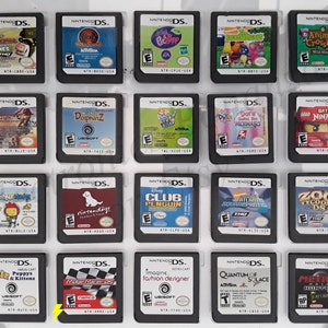 May include: A collection of 16 Nintendo DS game cartridges, displayed in a clear plastic case. The cartridges are arranged in four rows of four, with each cartridge featuring a different game title and cover art. Some of the games include "Animal Crossing: Wild World", "Lego Indiana Jones", "Club Penguin", "Metroid Prime Hunters", and "Ridge Racer DS".