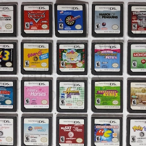 Puede incluir: Una colección de 20 cartuchos de juego de Nintendo DS, que incluyen títulos como Mario Kart DS, Cars y Toy Story 3. Los cartuchos están dispuestos en cuatro filas de cinco, con cada cartucho presentando un título de juego y una ilustración de portada diferentes.