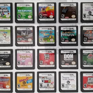 Puede incluir: Una colección de 18 cartuchos de juego de Nintendo DS, dispuestos en una cuadrícula de tres filas y seis columnas. Los cartuchos son todos negros con una ventana de plástico transparente que muestra el título del juego y la ilustración. Algunos de los juegos incluyen Super Mario Bros., Vet Collection, Tangled, Guitar Hero Decades y Brain Boost.